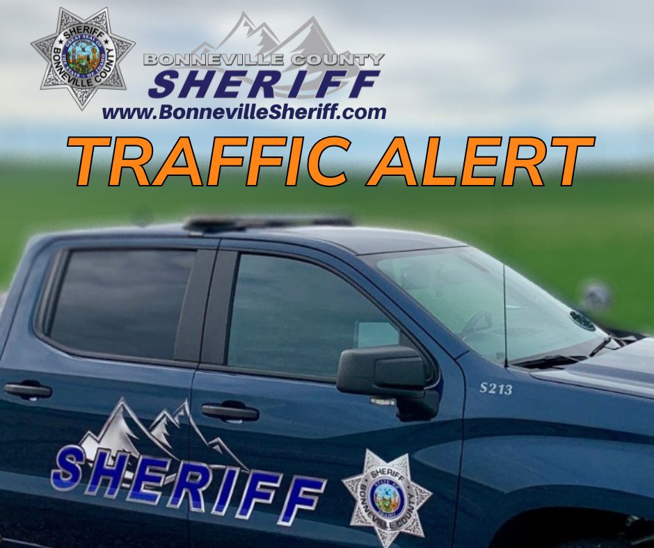 A Bonneville County Sheriff vehicle is parked in front of a grassy field, with "TRAFFIC ALERT" in large orange text and sheriff department logos and website displayed at the top.
