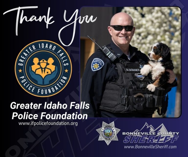 A smiling police officer in uniform holds a small black, white, and brown puppy. Logos for the Greater Idaho Falls Police Foundation and Bonneville County Sheriff appear, along with a thank you message and website links.