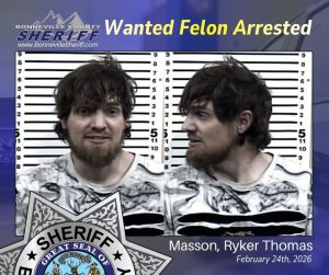 Two mugshots of a man with messy brown hair and a beard, wearing a white shirt with black patterns, appear side by side in front of a height chart. Text reads, "Wanted Felon Arrested, Masson, Ryker Thomas, February 24th, 2026.